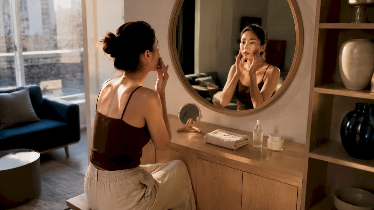 Een vrouw brengt in de badkamer een hydraterend serum op haar gezicht aan.