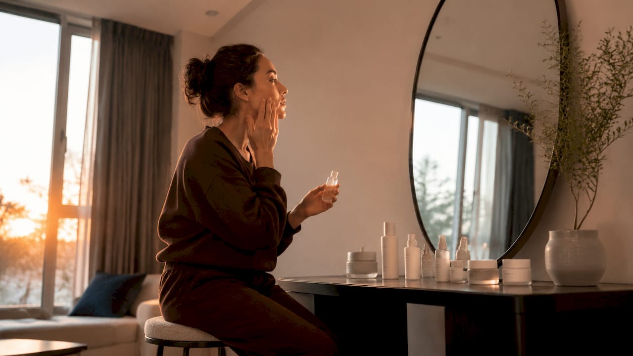 Een vrouw brengt haar favoriete K-beauty serum aan terwijl ze voor de spiegel in de badkamer staat.