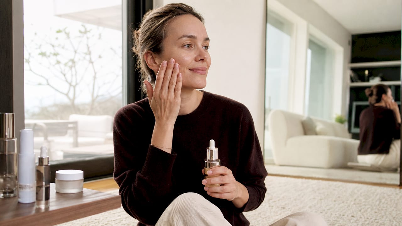 Een vrouw brengt een hydraterend serum aan op haar gezicht om haar huid te verzorgen.