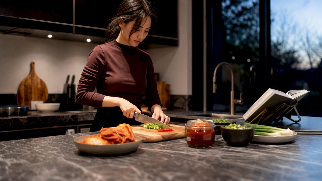 Een vrouw is in de keuken bezig met het klaarmaken van Koreaanse ingrediënten.